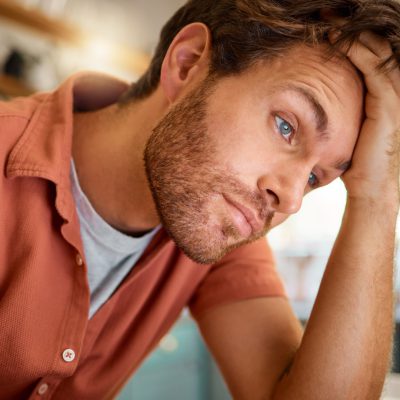 Young tired caucasian businessman working from home alone. One stressed businessman looking unhappy.